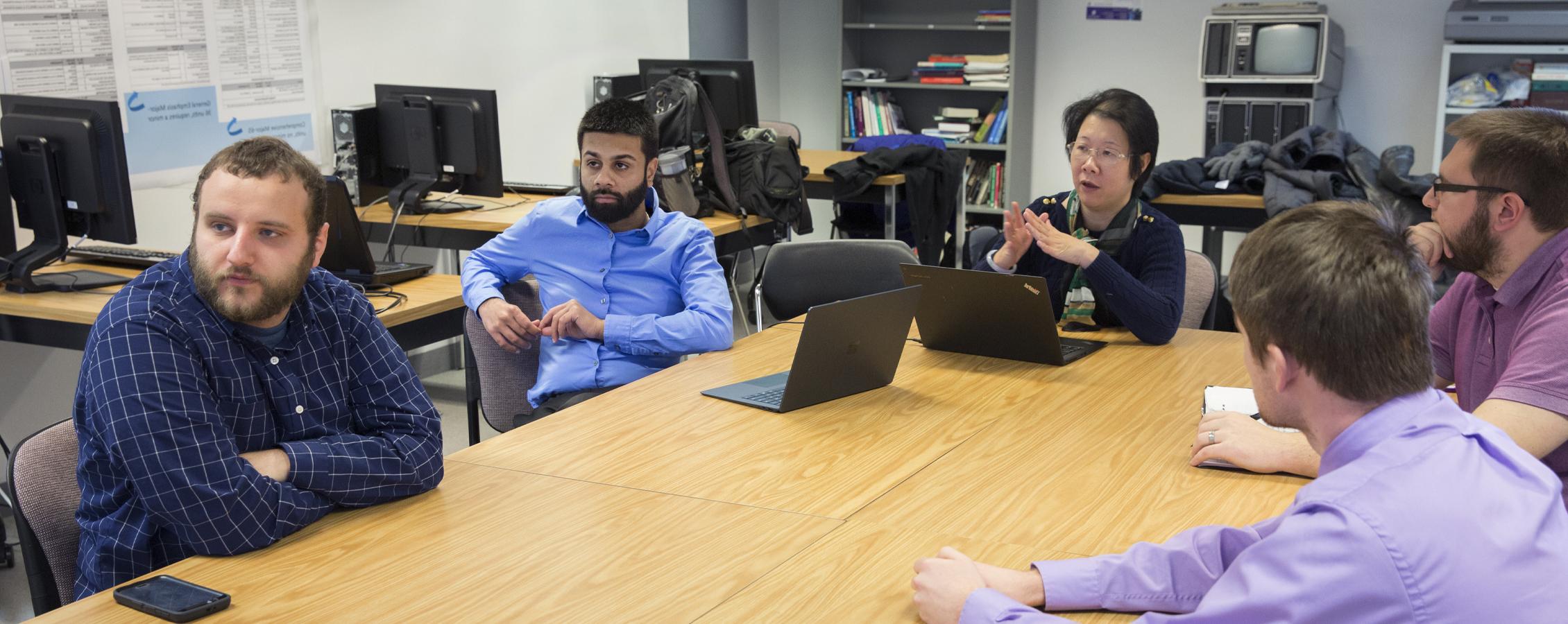 Students gather with a faculty member at a table.