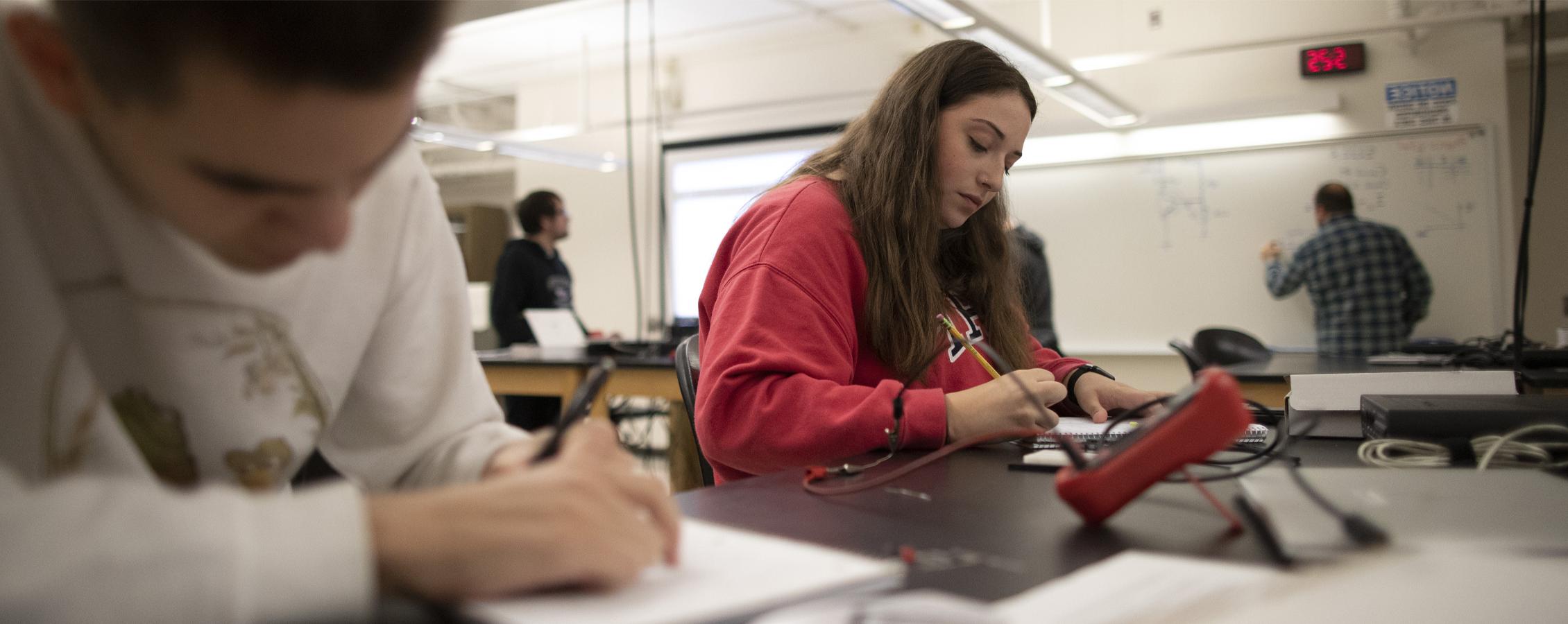 Students work together around a laptop.