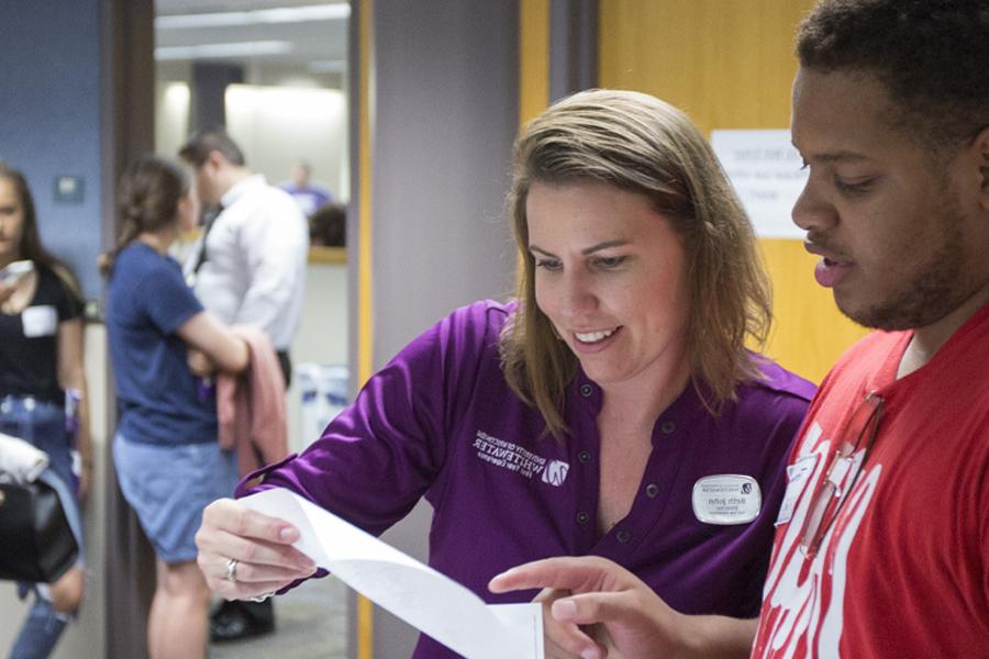 Beth John looks at a piece of paper with a student.