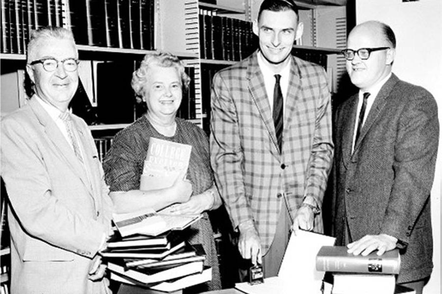 Helen Herbert standing among others in front of a bookshelf.