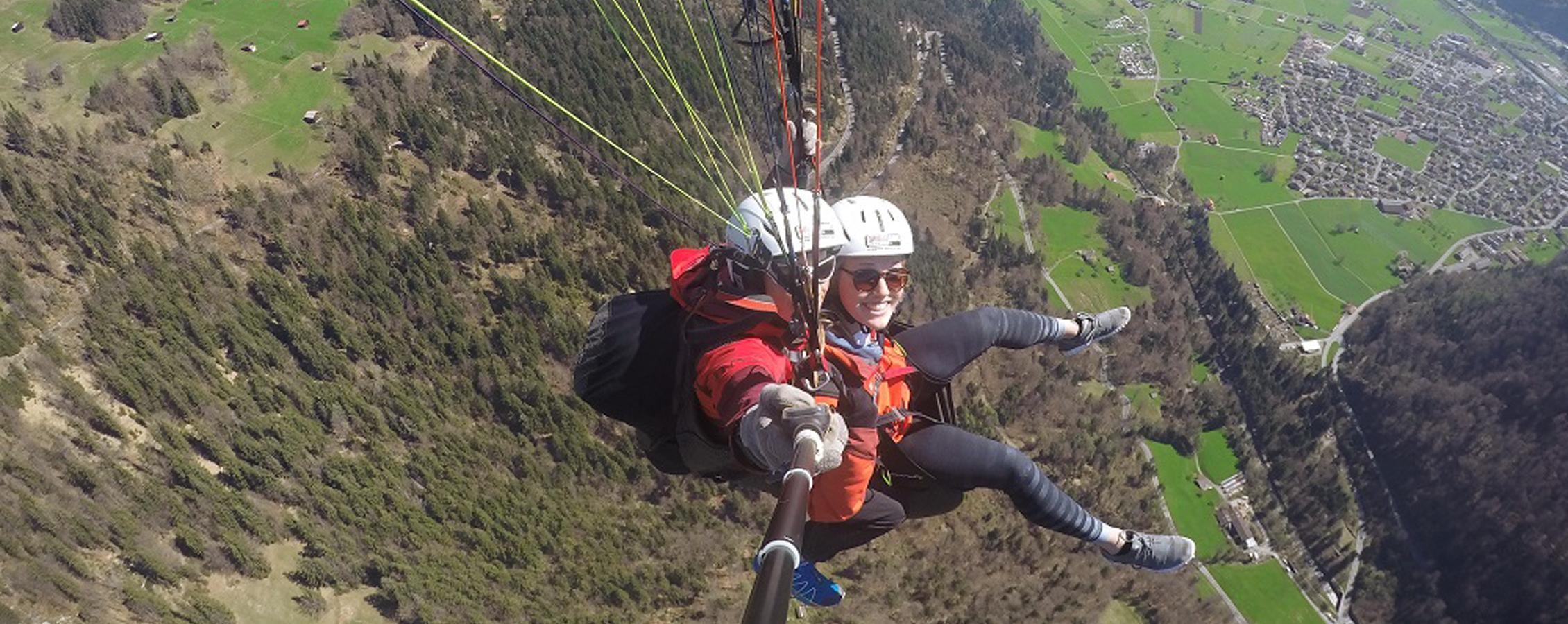 A person skydives while taking a selfie with a selfie stick.