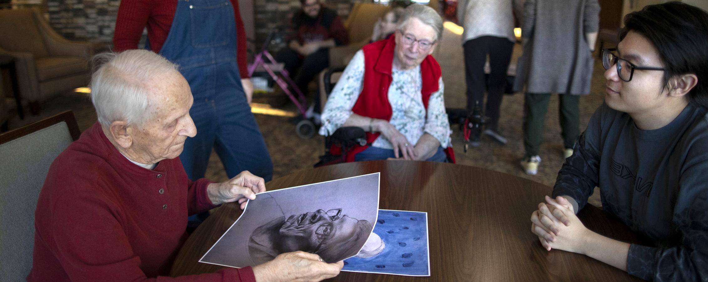 An international student hands a person a hand drawn portrait.