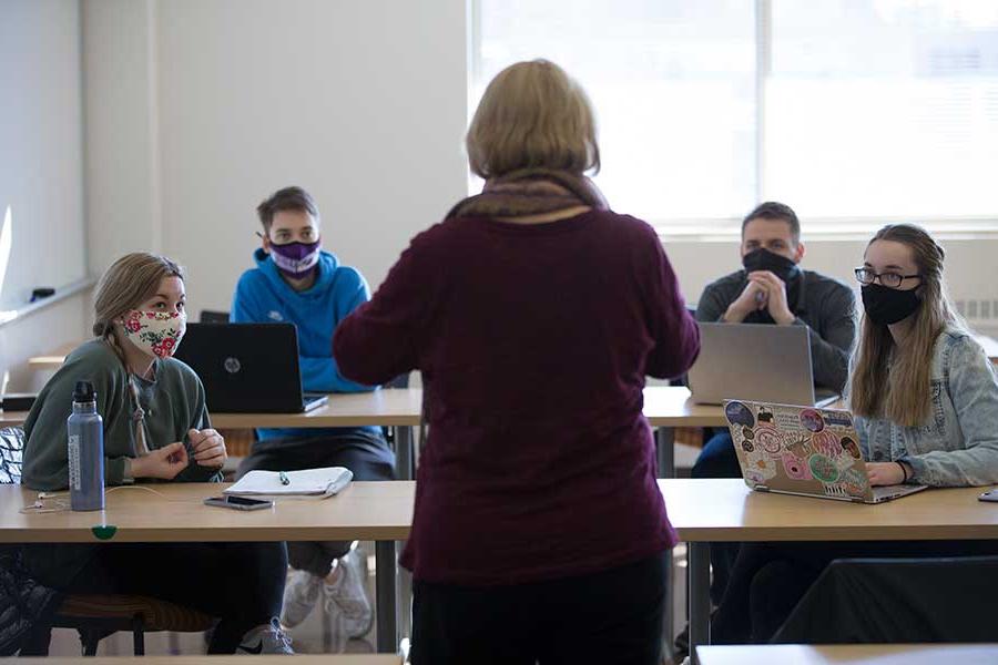 Matthews stands in a classroom full of students with her back to the camera.