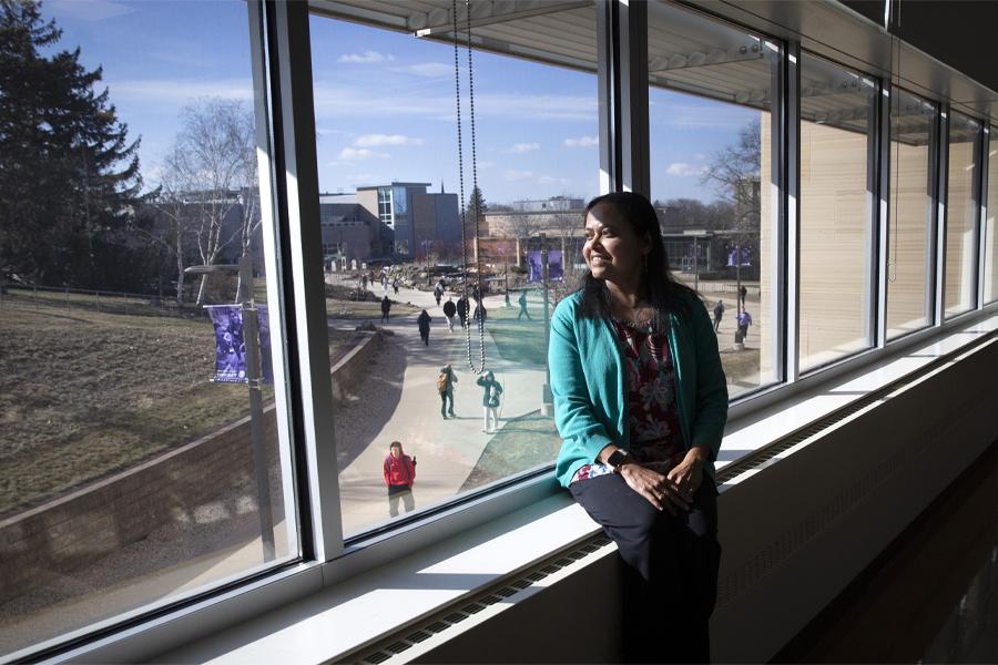 Rashiqa Kamal sits on a windowsill indoors and looks outside.