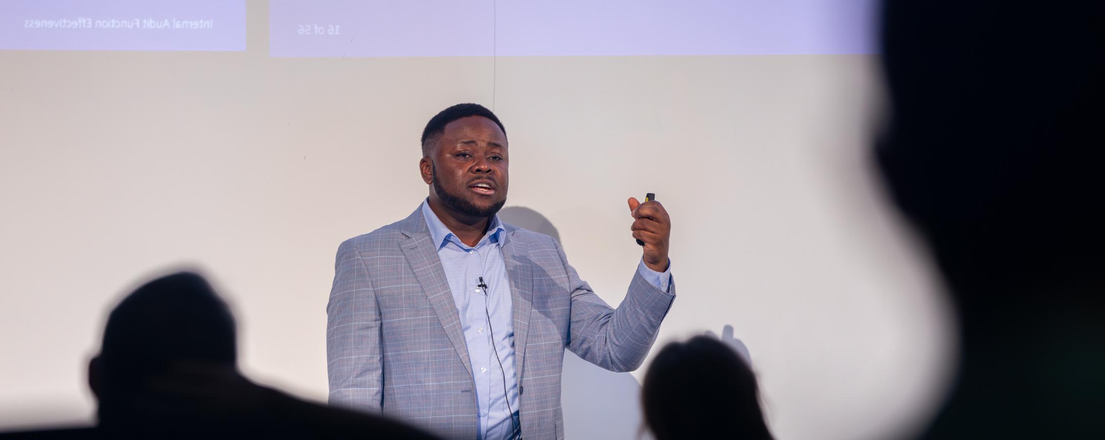 Patrice Achu defends his dissertation in front of a crowd.