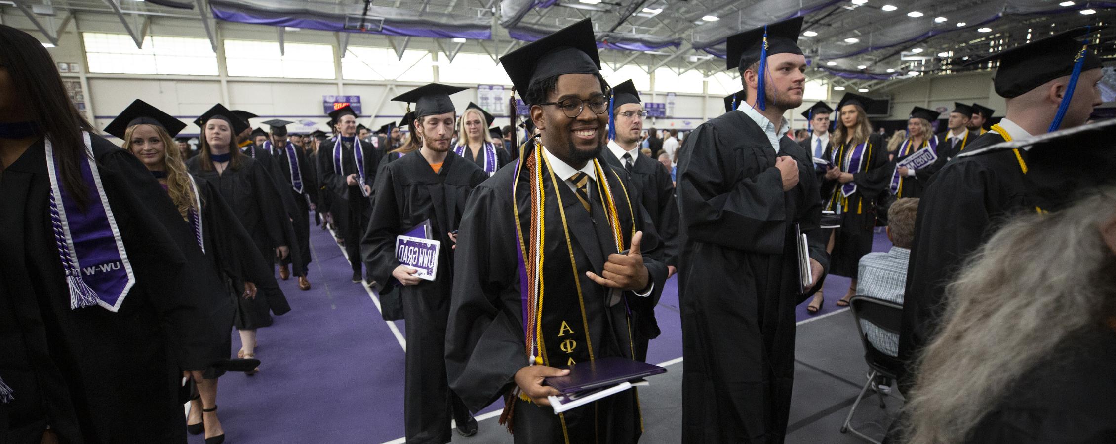 Graduates proceed down the aisles at Commencement in the fieldhouse.