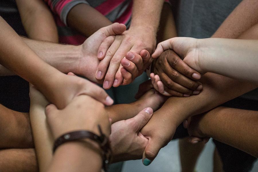 Hands of all sizes and colors hold hands.